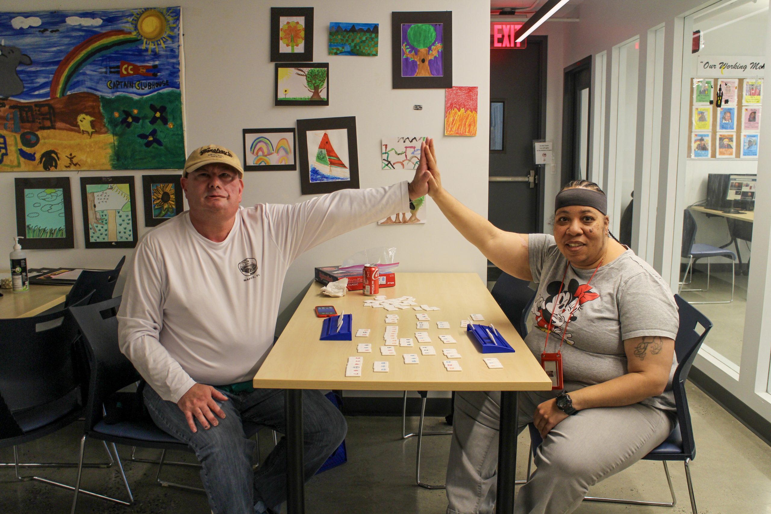 Two Clubhouse members giving each other a high five over the table while playing a game of Rumikub.